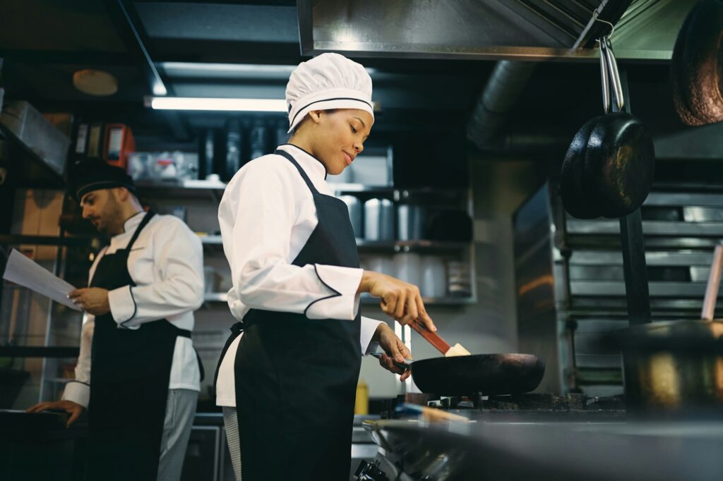 Below view of black female chef preparing food at restaurant.