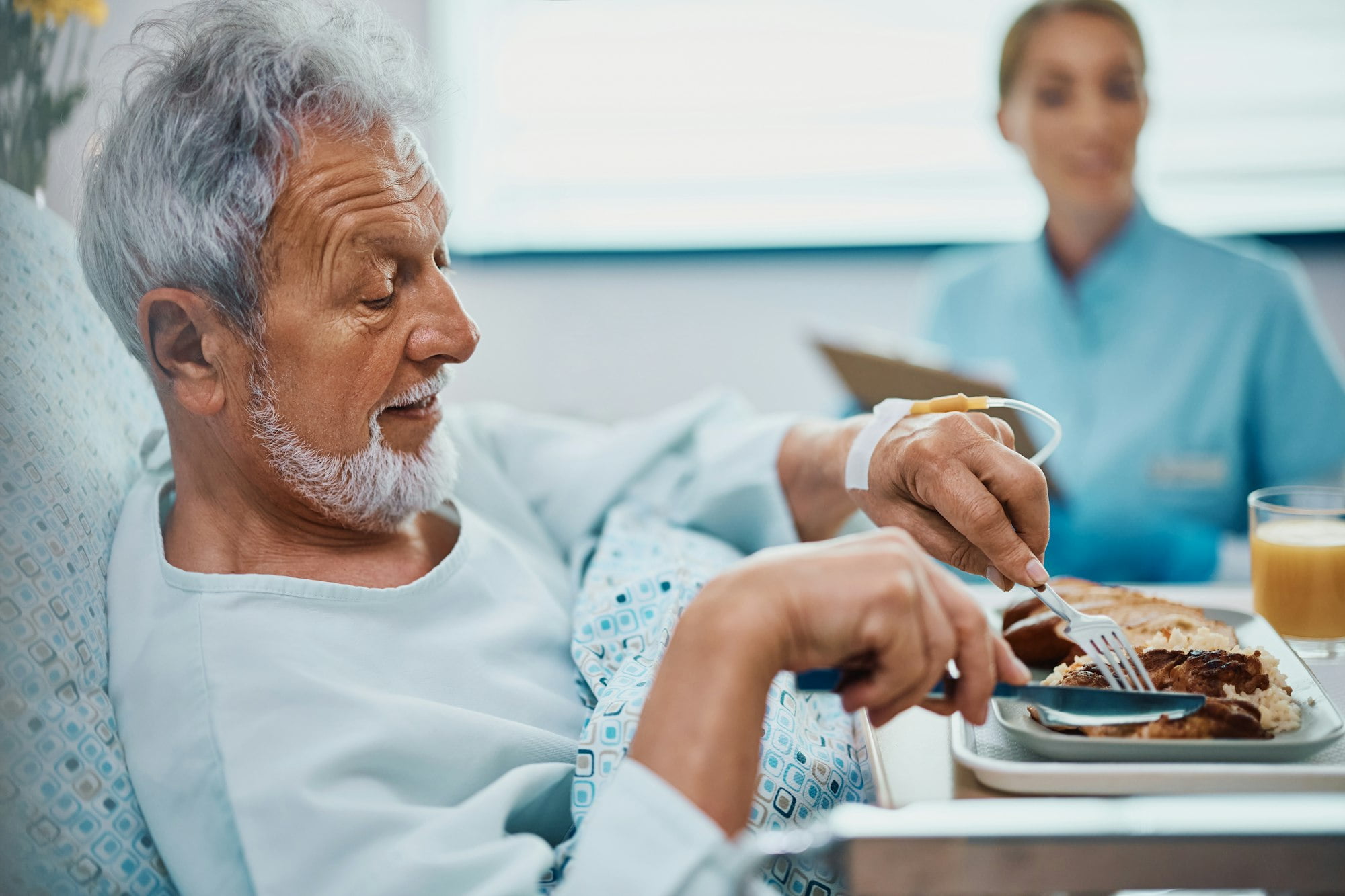 Senior man eating lunch while recovering at at hospital.