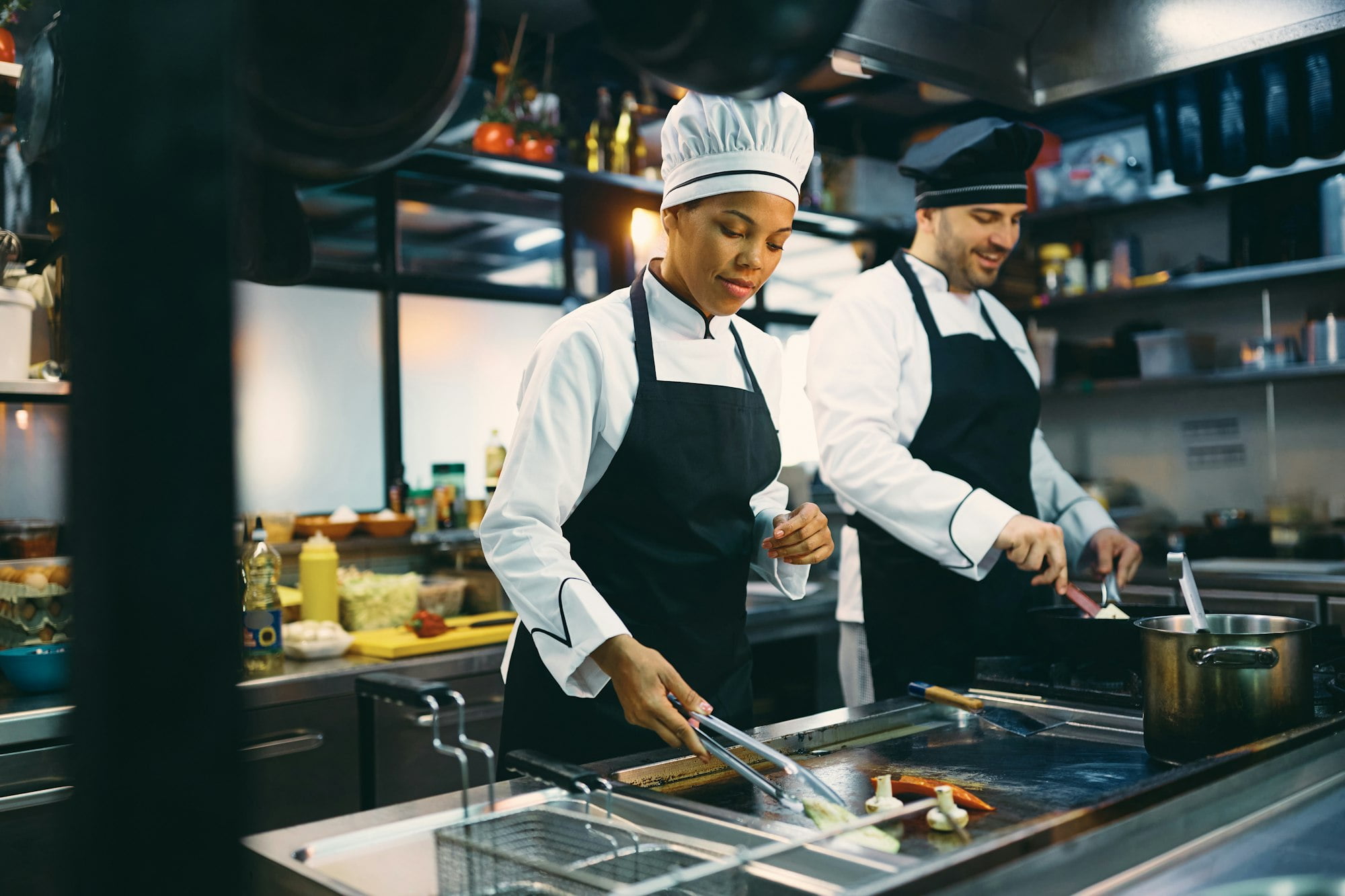 Two professional cooks preparing meal in the kitchen at restaurant.